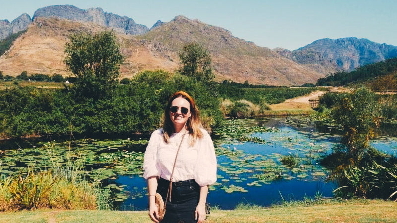Kate stands in front of a beautiful lake and mountains. She tells us about her fertility journey and challenges having a baby.