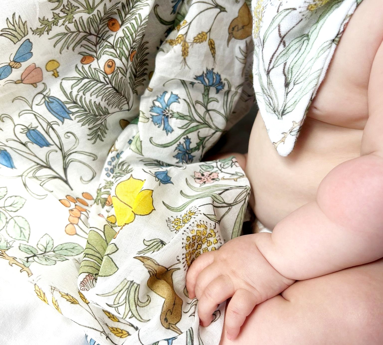 Baby wearing a floral-patterned outfit with a close-up of the fabric.
