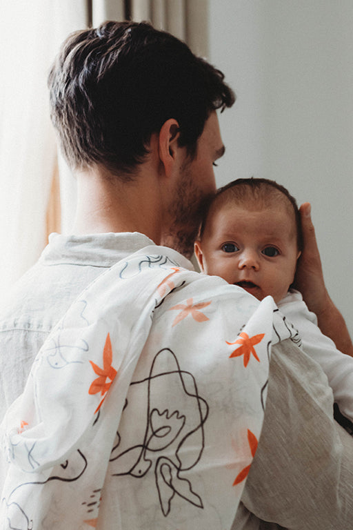 New Dad holding newborn baby girl with animal print muslin