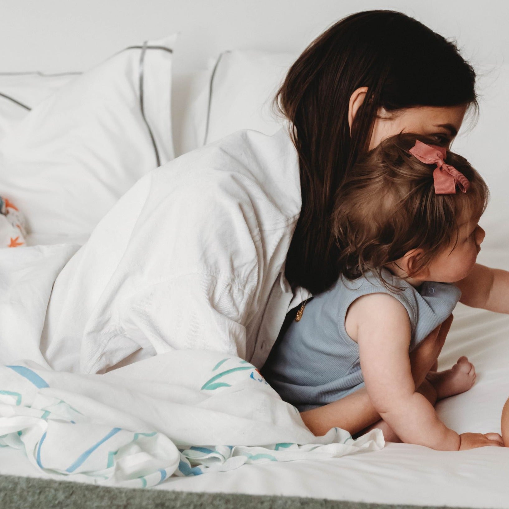 New mum with baby girl next to organic muslin blanket